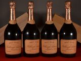 four bottles of wine are lined up on a red table