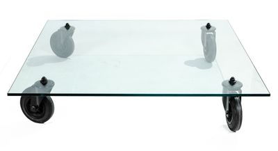 a glass coffee table with wheels and a vase on it