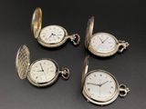 quatre montres de poche en argent posées sur une surface noire