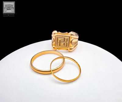two gold rings sitting on a white table