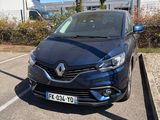 une voiture noire garée dans un parking à côté d'un bâtiment