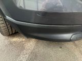 a teddy bear sitting on the bumper of a car