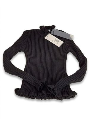 Le pull est noir, avec des volants et une étiquette.