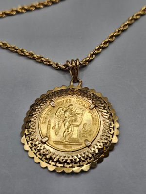 un gros plan d'une pièce d'or suspendue à une chaîne en or