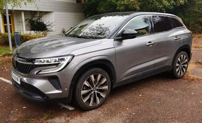 the silver suv is parked in the parking lot near a building