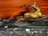 une statue en bronze représentant un cerf et un chien en pleine course, posée sur un socle en marbre