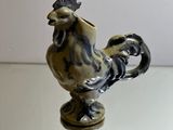 une figurine représentant un coq posée sur une table en verre