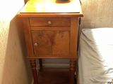a small table with a lamp on top of it next to a bed