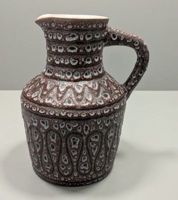 un vase marron et blanc muni d'une anse, posé sur une table