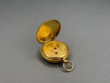 an old gold pocket watch sitting on top of a gray surface