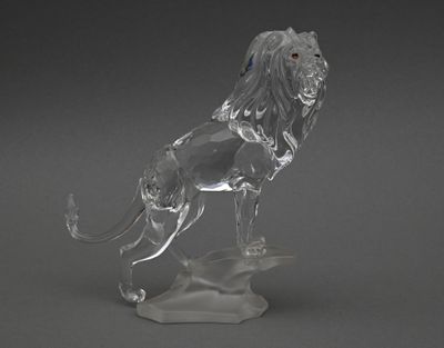 figurine en cristal représentant un lion sur un rocher, sur fond gris