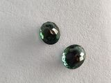 a pair of green tourmaline gems on a white surface