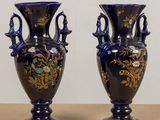 pair of blue vases with gold designs on them sitting on a table