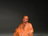 une vieille figurine sculptée représentant un homme assis sur une chaise