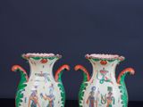 une paire de vases chinois posés sur une table noire, devant un fond sombre