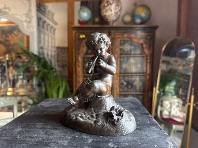 a statue of a boy playing a flute on a table