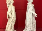 two white statues of women in a red room with a red wall