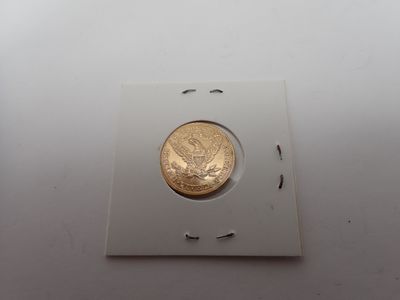 une pièce d'or dans une boîte blanche posée sur une surface blanche