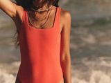 une femme debout sur la plage avec une planche de surf