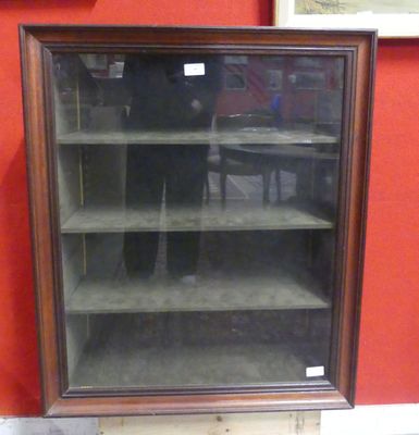 une vitrine en verre avec des étagères, placée dans un coin de la pièce
