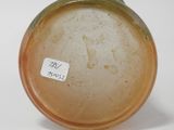 a brown vase with a label on it on a white surface