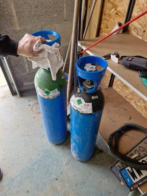 un homme qui se tient à côté de deux bouteilles de gaz
