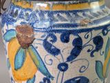 a blue and yellow vase with a handle on a table