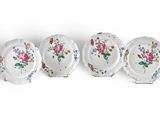 four plates with flowers on them are lined up against a white background