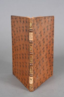 un vieux livre posé sur une table à côté d'un mur gris