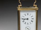 an image of a small brass clock with a key on a table