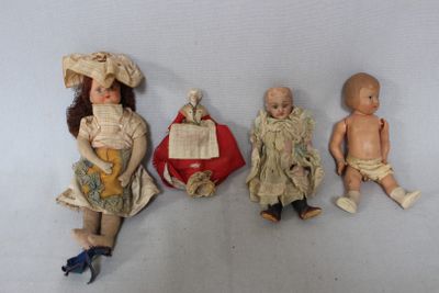 three antique dolls sitting next to each other on a white surface