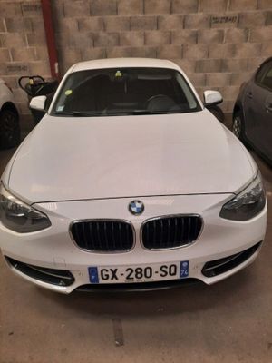 une BMW blanche garée dans un garage, avec d'autres voitures en arrière-plan