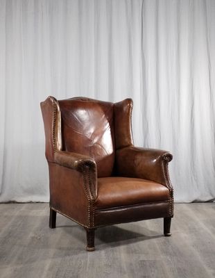 une image représentant un fauteuil en cuir marron posé sur un parquet en bois massif