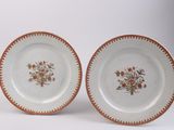 two plates with floral designs on them sitting on a white surface