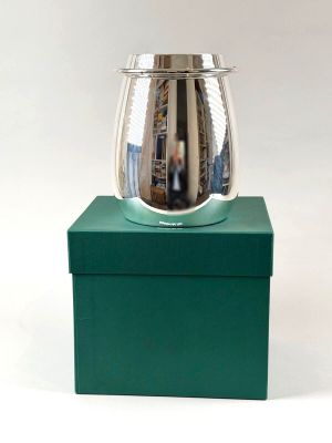a green box with a silver vase on top of it