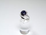 a ring with a blue stone in it sitting on a clear glass