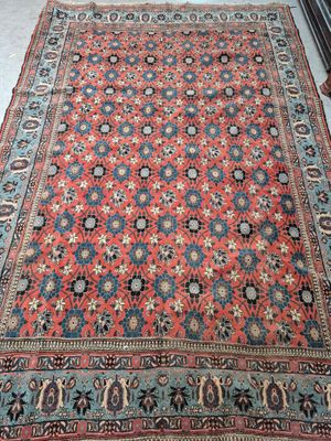 a red and blue rug on a floor next to a chair