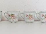 many cups and saucers lined up on a table