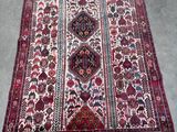 un tapis oriental exposé dans une pièce où se trouve une chaise