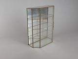 une vitrine en verre avec des bordures dorées et des étagères, posée sur un socle blanc