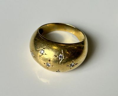 une bague en or sertie de diamants, posée sur un fond blanc