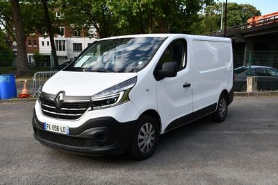 La camionnette blanche est garée sur le parking, près de quelques arbres.