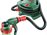 Le pistolet de peinture vert et rouge se trouve à côté d'un tuyau rouge et noir