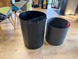 two trash cans sitting on the floor next to each other