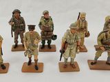 six figurines of soldiers with weapons and uniforms on a white surface