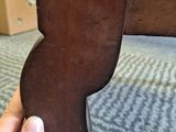 a hand that is holding a piece of wood in front of a bed