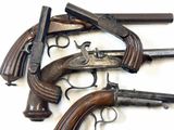Plusieurs vieilles armes à feu sont alignées sur une surface blanche