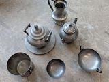 four silver tea pots and two silver teapots on the floor