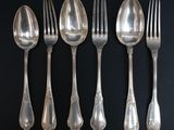 six cuillères et six fourchettes sont alignées sur une surface noire