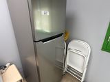 un réfrigérateur argenté à côté d'une chaise blanche dans une pièce